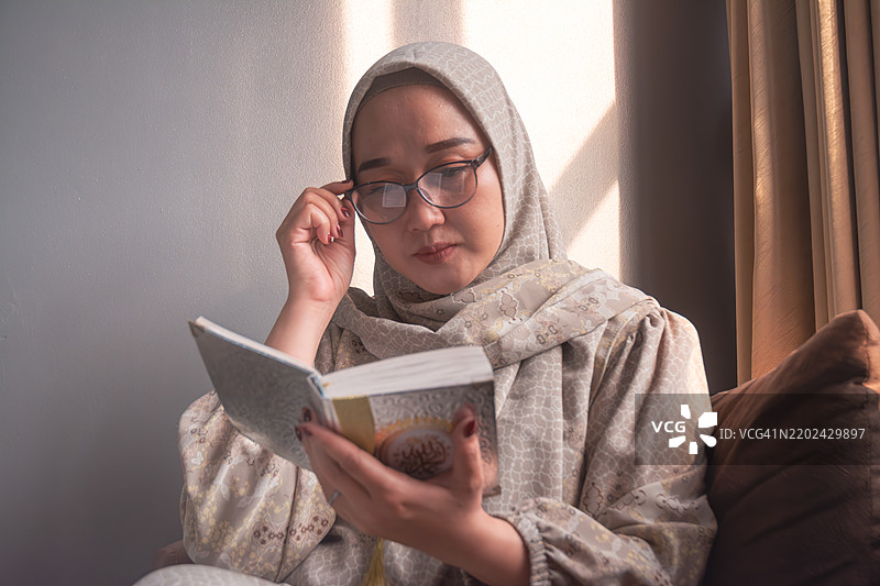 东南亚女性在午后阳光下在家诵读《古兰经》| 宗教主题图片素材