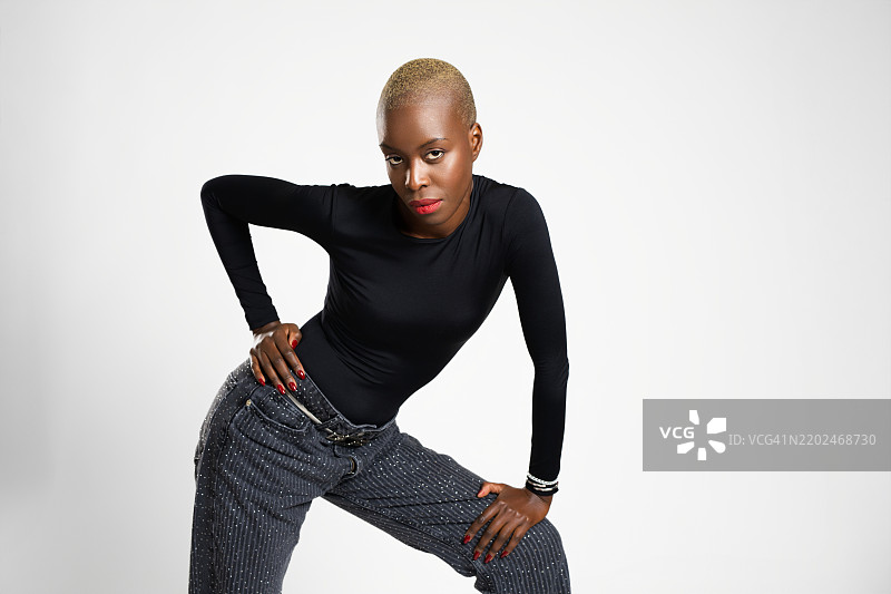 时尚模特在摄影棚中摆姿势，双手放在臀部和膝盖上图片素材