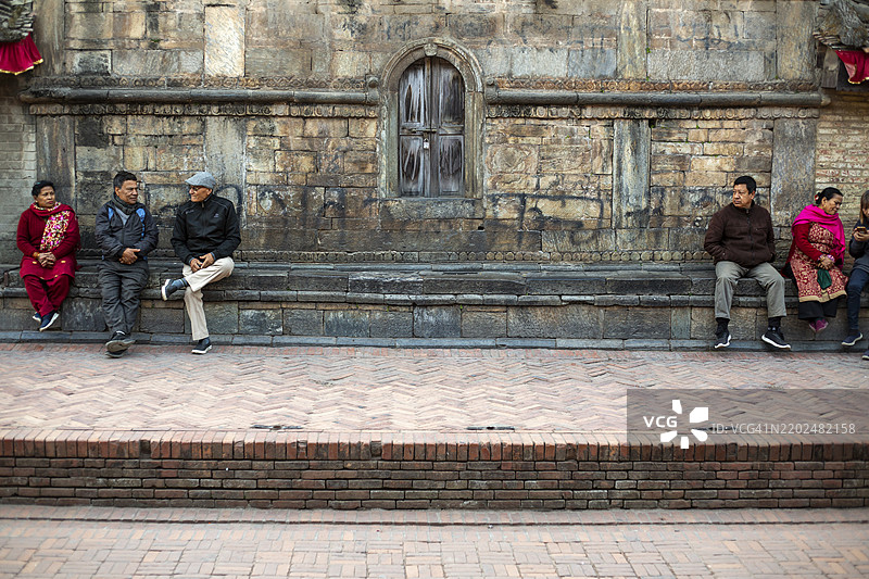 人们坐在尼泊尔加德满都帕坦杜巴广场的新ar建筑外。图片素材