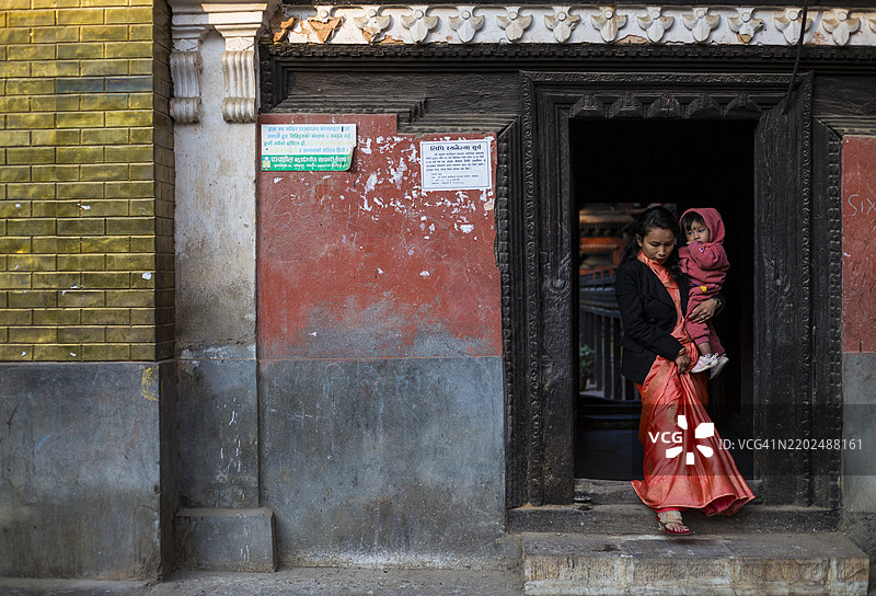一个人走出位于尼泊尔加德满都帕坦杜巴广场附近的奥库巴哈尔鲁德拉瓦尔纳大寺的入口。图片素材