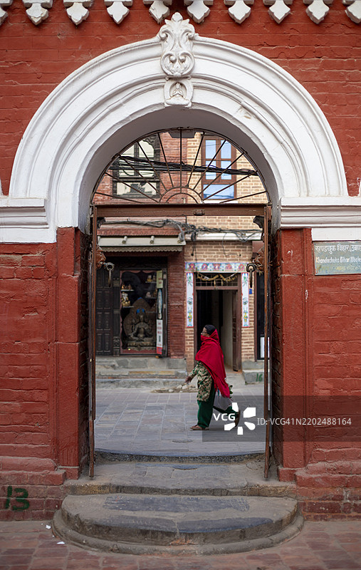 一个人走过位于尼泊尔加德满都帕坦杜巴广场附近的奥库巴哈尔鲁德拉瓦尔纳大寺的入口。图片素材