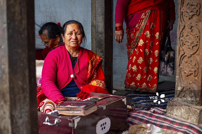 一位朝圣者在尼泊尔加德满都的帕坦杜巴广场的克里希纳寺前摆姿势拍照。图片素材
