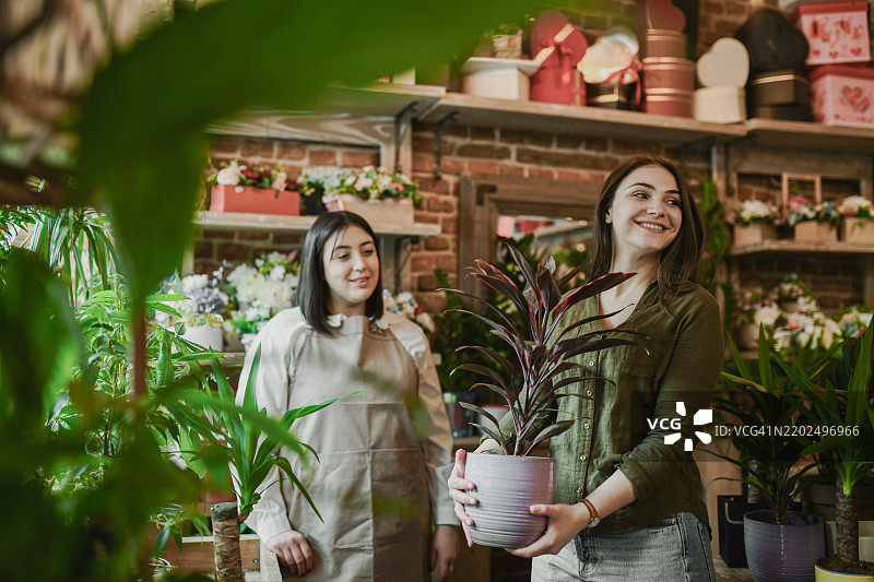 可爱的女性顾客在花店里提着花盆，开心地找到完美的植物图片素材