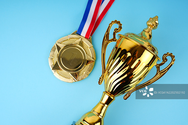 蓝色背景上的金色奖杯和奖牌图片素材