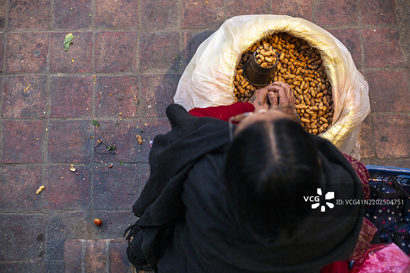 一位街头小贩在尼泊尔加德满都的帕坦杜巴广场出售花生。图片素材