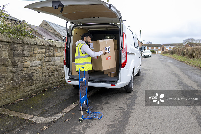 快递员在卸货车时分类包裹图片素材