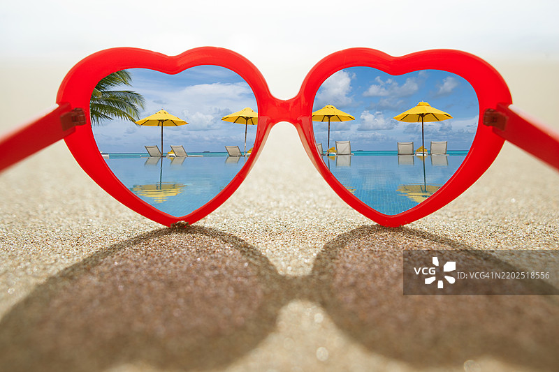心形太阳镜注视着游泳池和遮阳伞图片素材