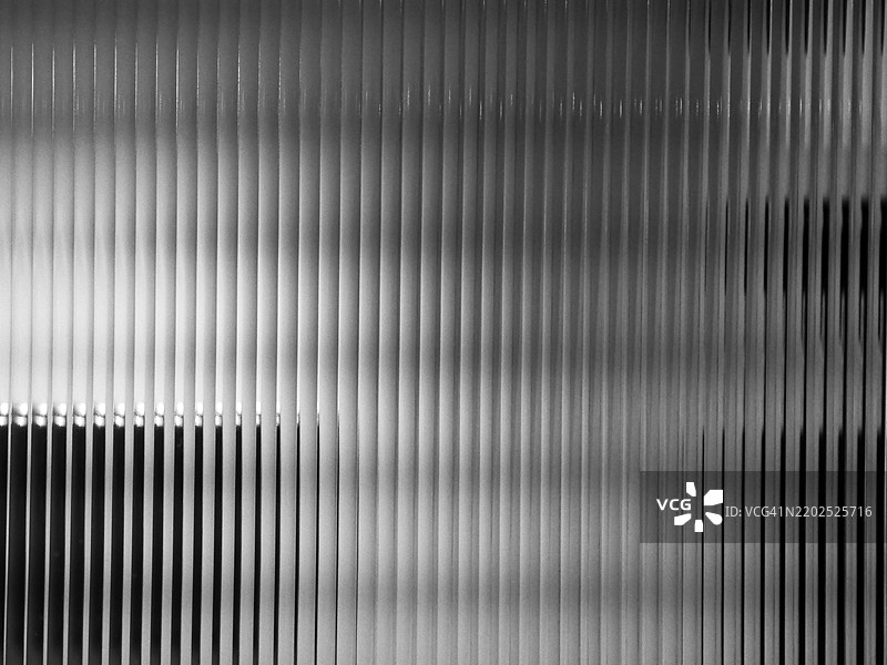 背光的条纹状不透明窗户特写。自然阴影。黑白色调。图片素材