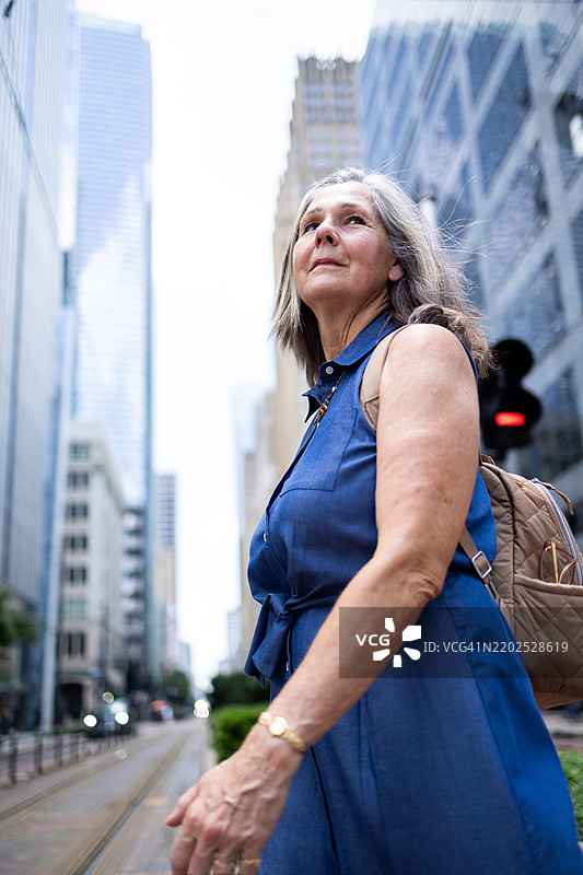 自信的成熟的女性在现代摩天大楼和电车轨道的城市环境中图片素材