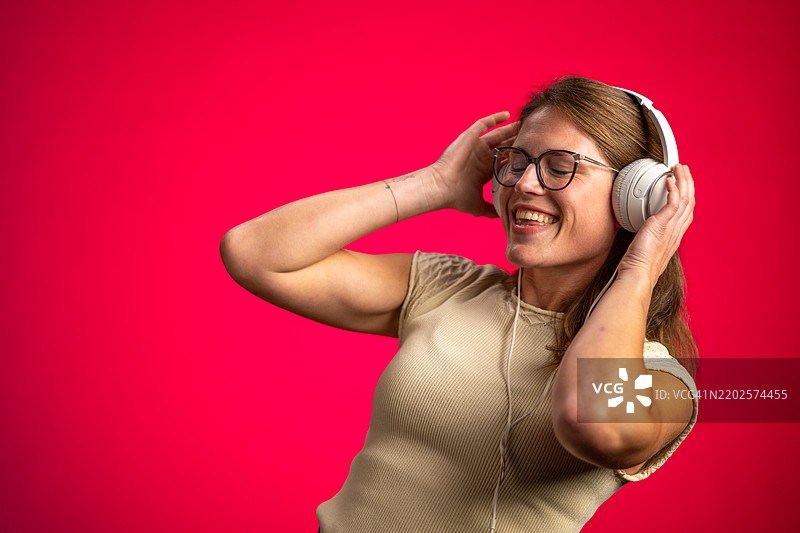 快乐的白人女性在充满活力的工作室里听音乐图片素材