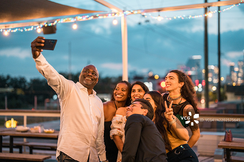 多元化的朋友们在餐厅露台上享受自拍时刻图片素材