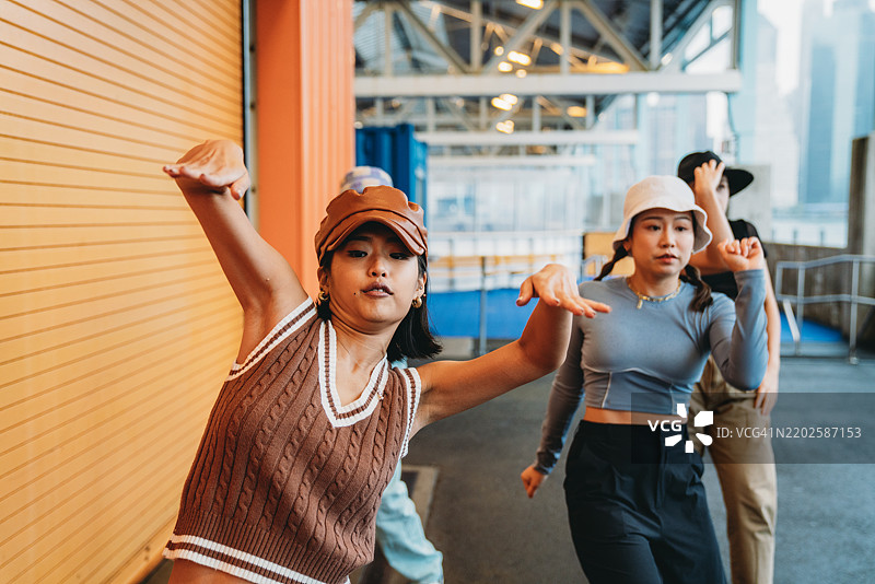 一群女性舞者在橙色墙壁前快乐地跳舞图片素材