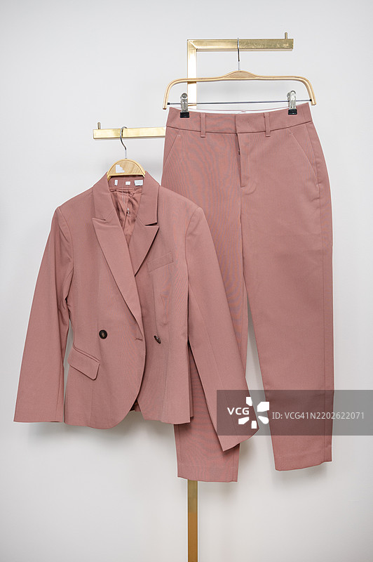 一套粉色西装和裤子挂在衣架上图片素材