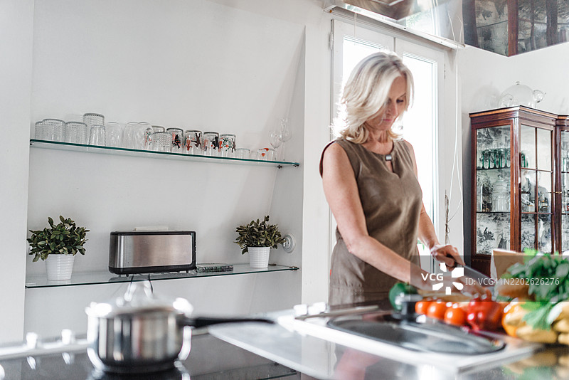 成熟的女性在家厨房准备午餐图片素材