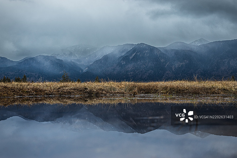 在阴郁的日子里，埃斯特山脉的倒影映照在穆尔瑙沼泽中。德国巴伐利亚州穆尔瑙。图片素材
