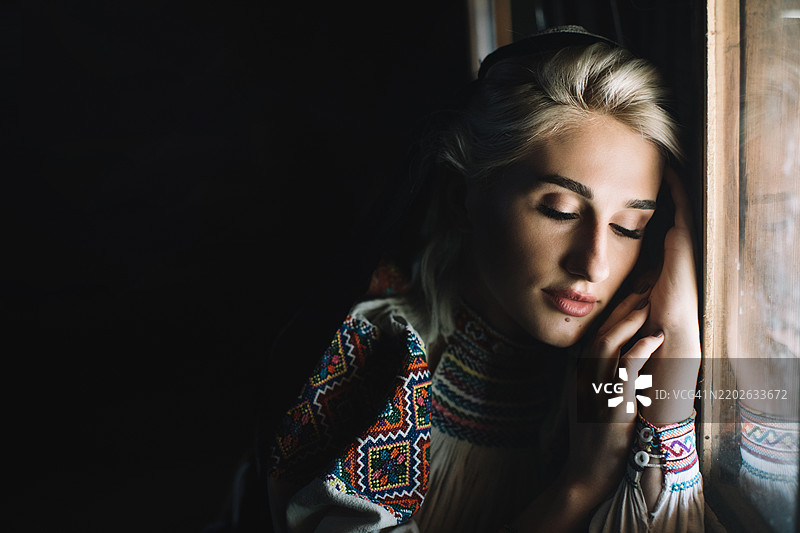 一个美丽的年轻女孩在窗边享受阳光。图片素材