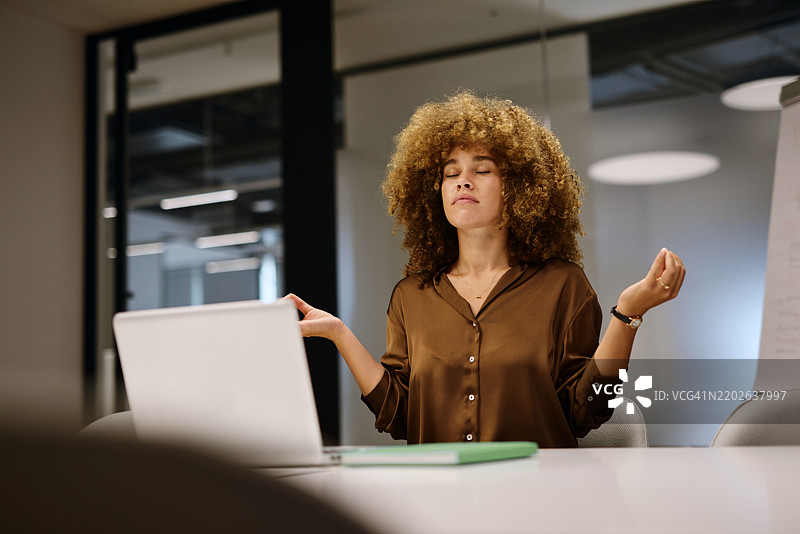 现代办公室里，女商人在桌前冥想图片素材