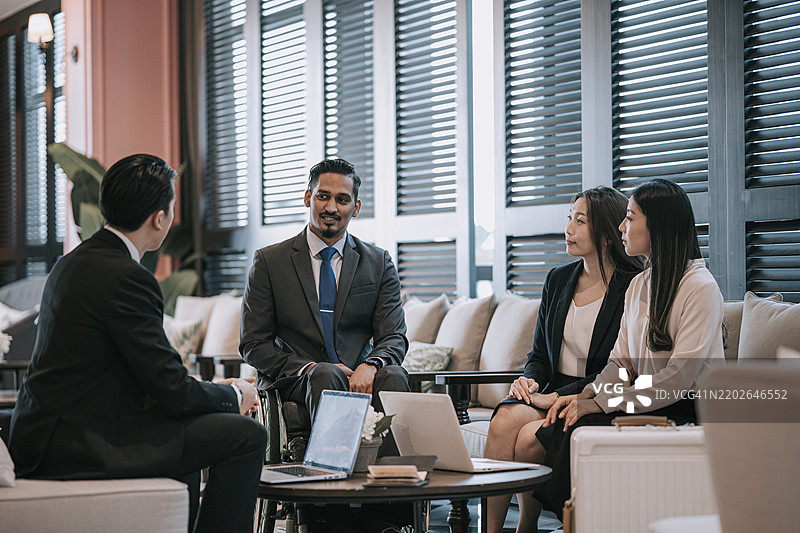 坐在轮椅上的印度商人在休息室与同事进行商务会议图片素材