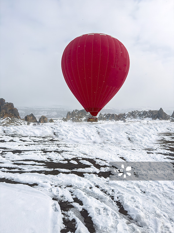 冬季红色热气球飞越卡帕多奇亚的仙女烟囱。图片素材