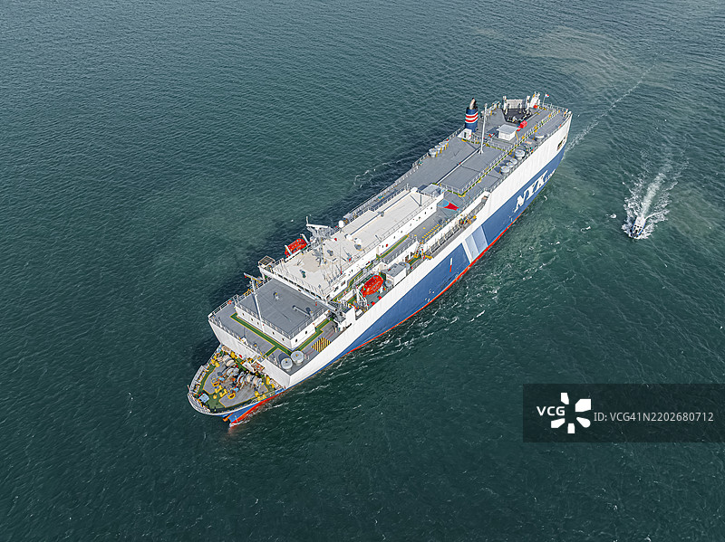 航拍视角，大型船只驶出货物港口。通过汽车驳船运输到外国的业务，海上运输成品汽车。图片素材