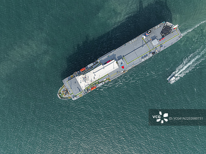 航拍视角，大型船只驶出货物港口。通过汽车驳船运输到外国的业务，海上运输成品汽车。图片素材
