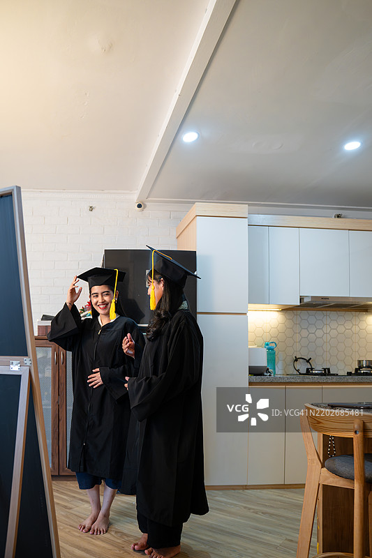 两位年轻女性在家准备毕业，正对着镜子。图片素材