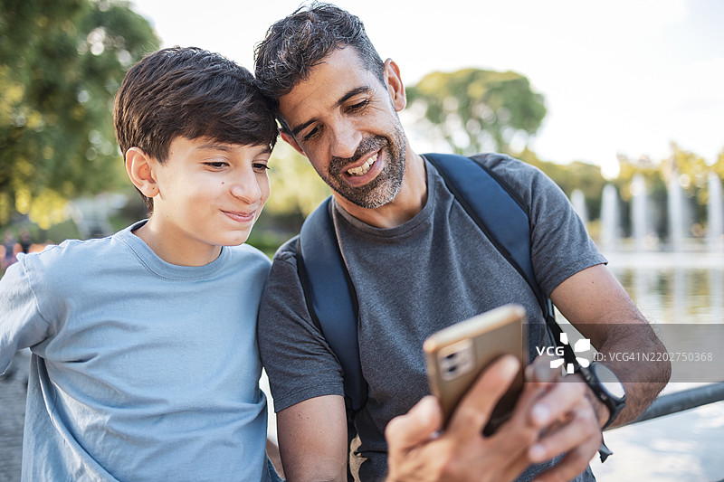 父亲和儿子一起享受查看手机照片的时光图片素材
