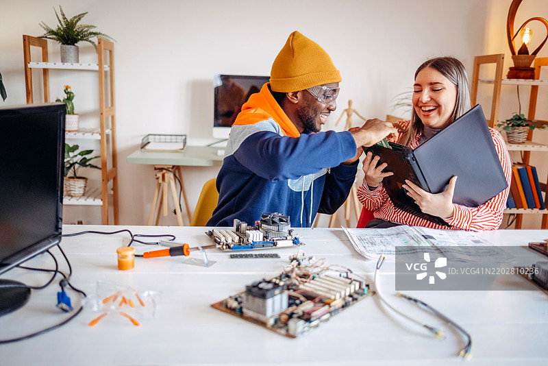 朋友们在家一起修理笔记本电脑图片素材