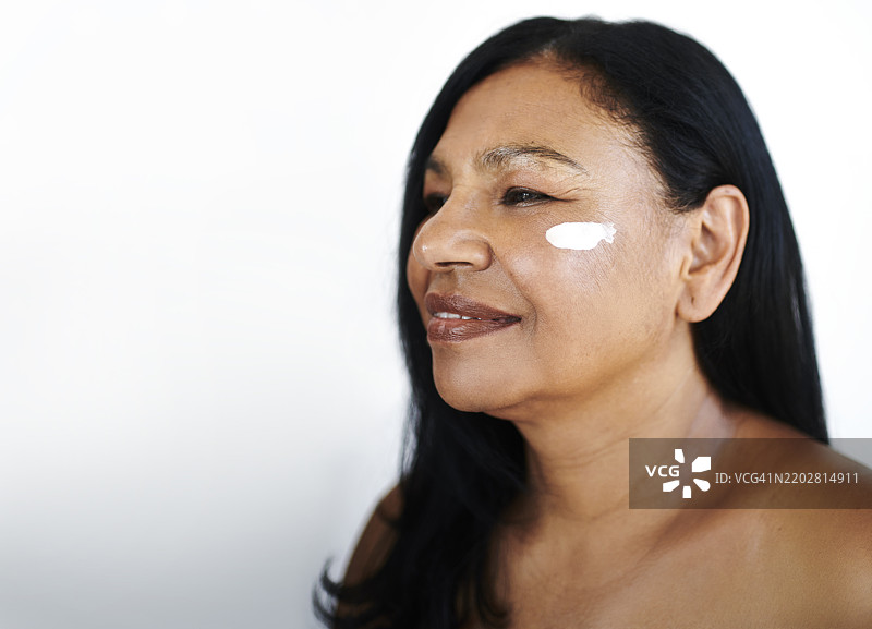 微笑的中年女性涂抹护肤霜图片素材