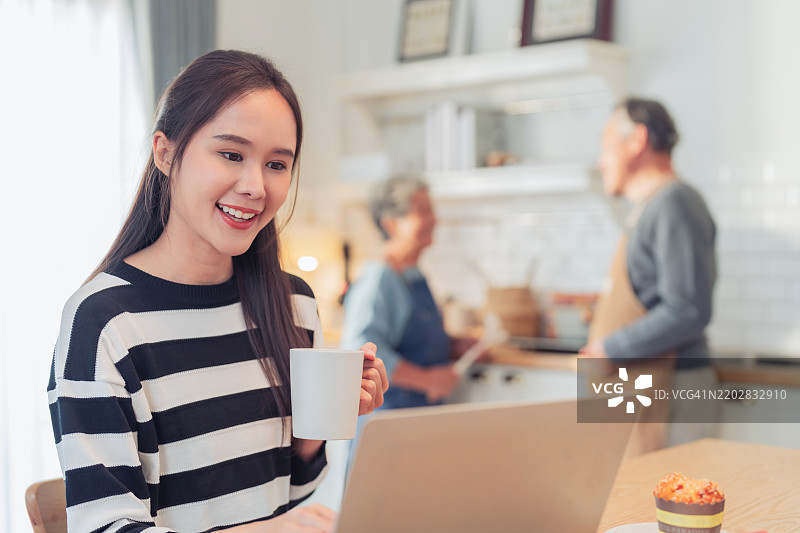 快乐的孙女在家工作，她来探望祖父母，幸福的家庭关系，亚洲家庭，祖父母在家为他们的侄子做饭。图片素材