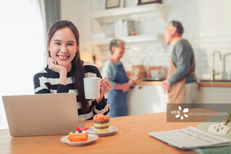 快乐的孙女在家工作，她来探望祖父母，幸福的家庭关系，亚洲家庭，祖父母在家为他们的侄子做饭。图片素材