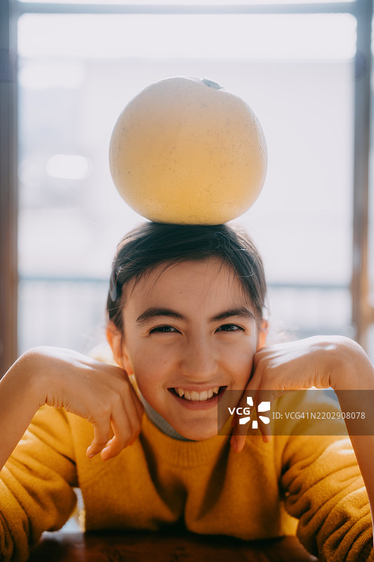 头上戴着柚子的快乐小女孩图片素材