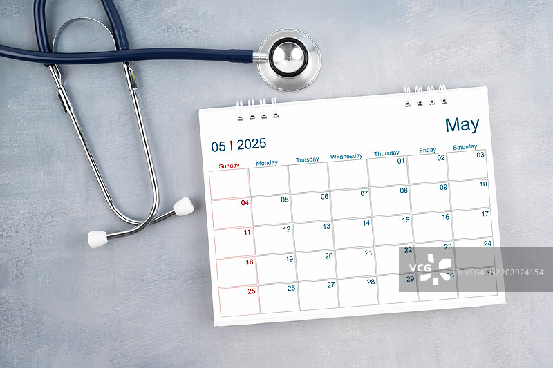 2025年5月的桌面日历和听诊器，医生预约概念。平铺展示。图片素材