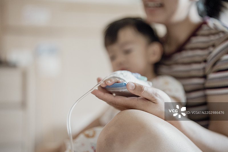 亚洲母亲正在使用温度计为她的儿子测量体温图片素材
