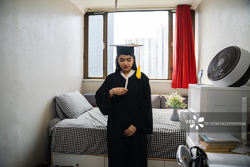 女孩在卧室里穿着学位服和学士帽图片素材