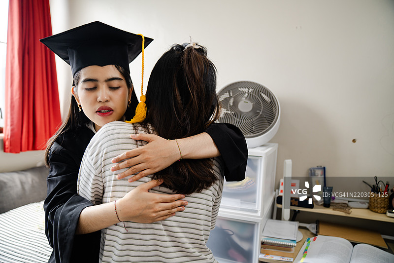 微笑的姐妹在毕业典礼上比出和平手势图片素材