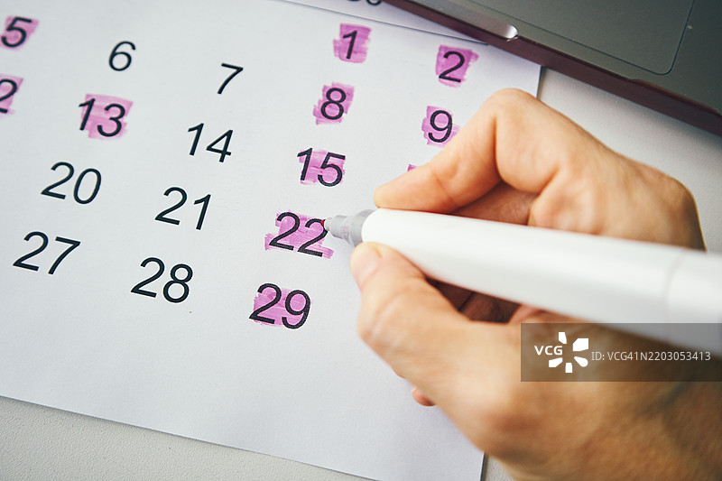 用记号笔在日历上标记重要日期的人图片素材