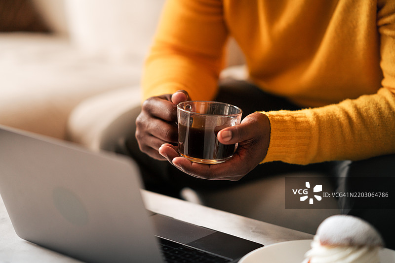 男人在家中享受咖啡和糕点，同时使用笔记本电脑工作图片素材