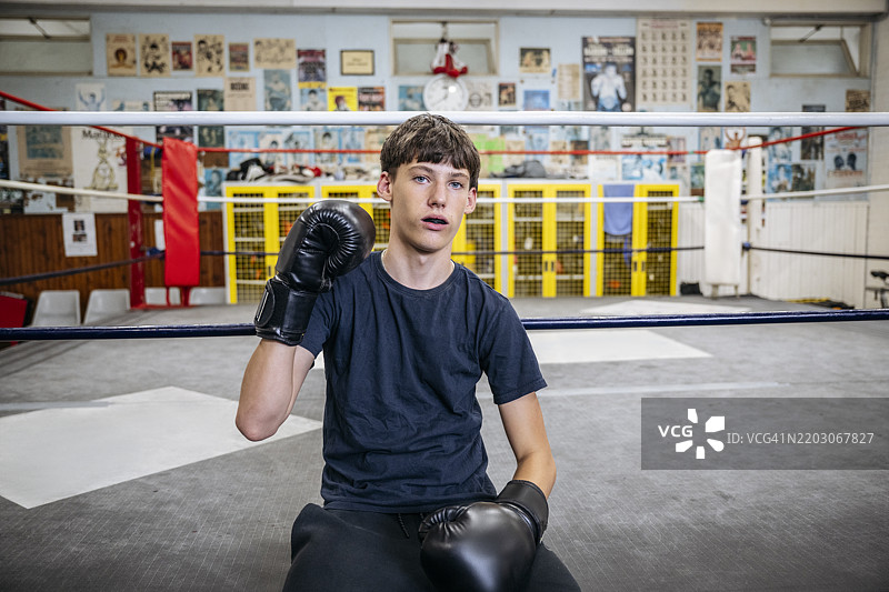 拳击场边的少年肖像，举起拳击手套的拳头图片素材