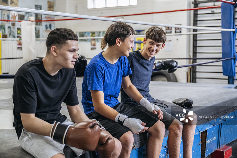 年轻的拳手并肩坐在擂台边缘图片素材