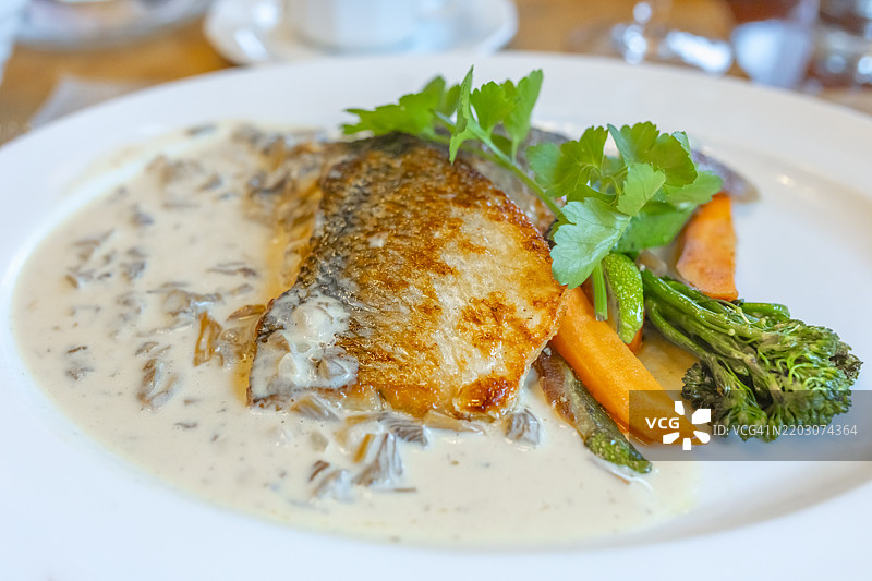 美味的传统芬兰鱼菜，炸白鱼配奶油喇叭菇酱和新鲜蔬菜，摆放在白色盘子上图片素材