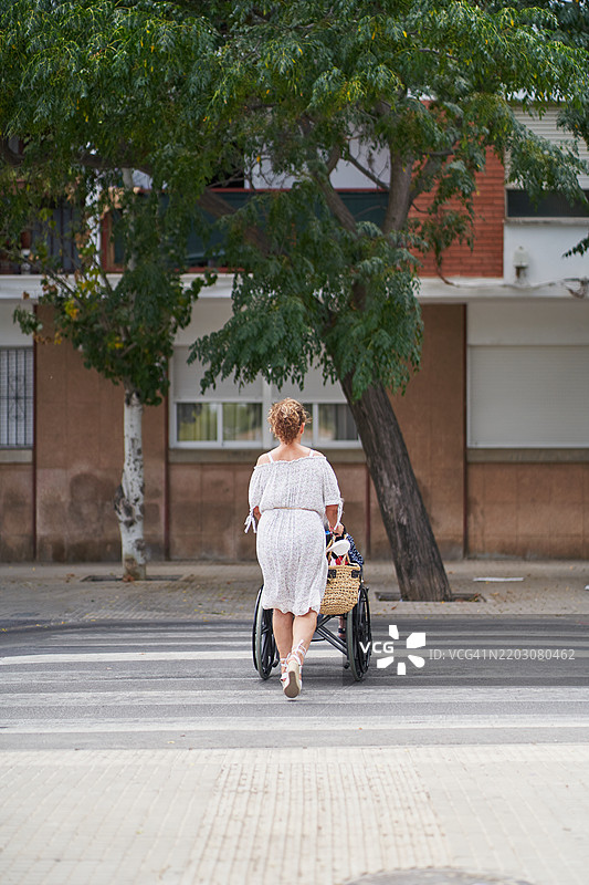 女人推着年迈的母亲在斑马线上行走图片素材