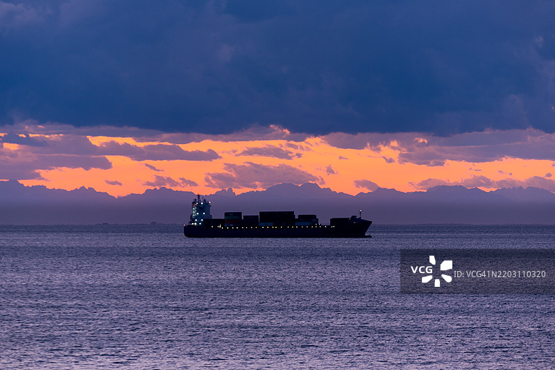 日落时分，海面上船只的剪影与天空相映成趣图片素材
