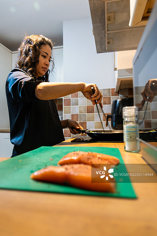 亚洲女士在英国布里斯托准备健康的三文鱼餐。图片素材