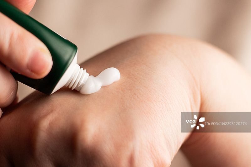女人在手上涂抹护手霜 近距离拍摄白色护手霜 从管子挤出护手霜 柔软的手和护肤概念图片素材