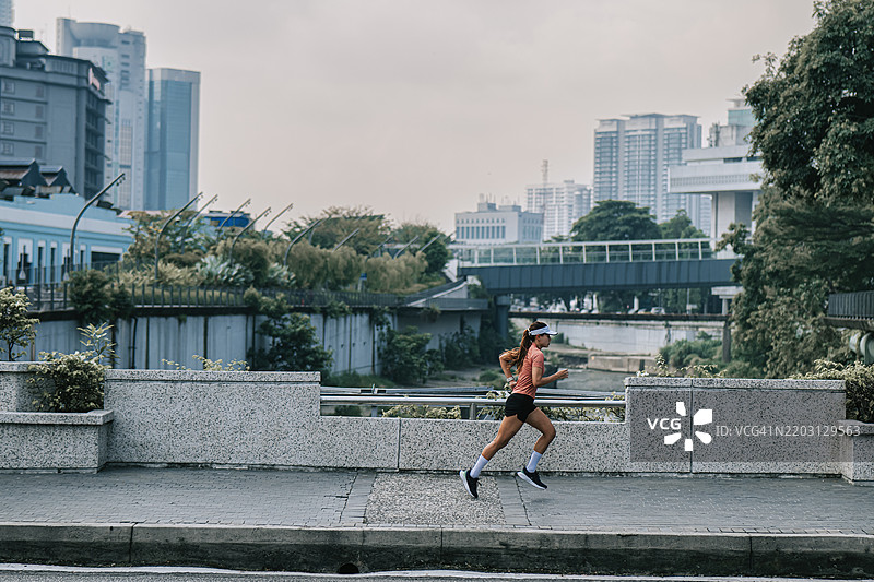 在吉隆坡市的克朗河上奔跑的亚洲华裔女性跑者图片素材