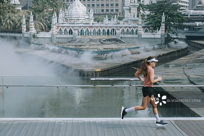 亚洲华裔女性运动员在早晨跑步经过苏丹阿卜杜勒·萨马德清真寺图片素材