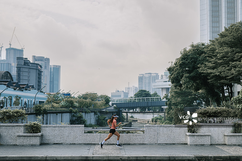 在吉隆坡市的克朗河上奔跑的亚洲华裔女性跑者图片素材
