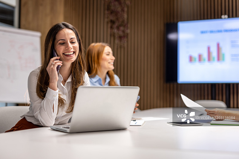 在办公室会议中微笑的女商人一边打电话图片素材