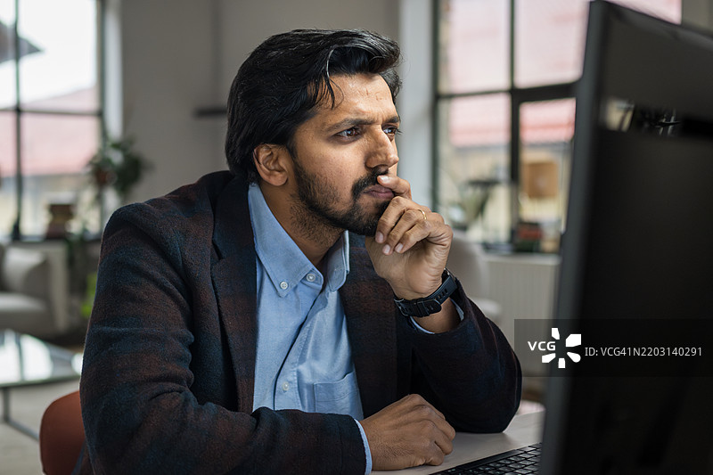 在明亮的办公室里，忧虑的印度商人正在使用电脑工作图片素材